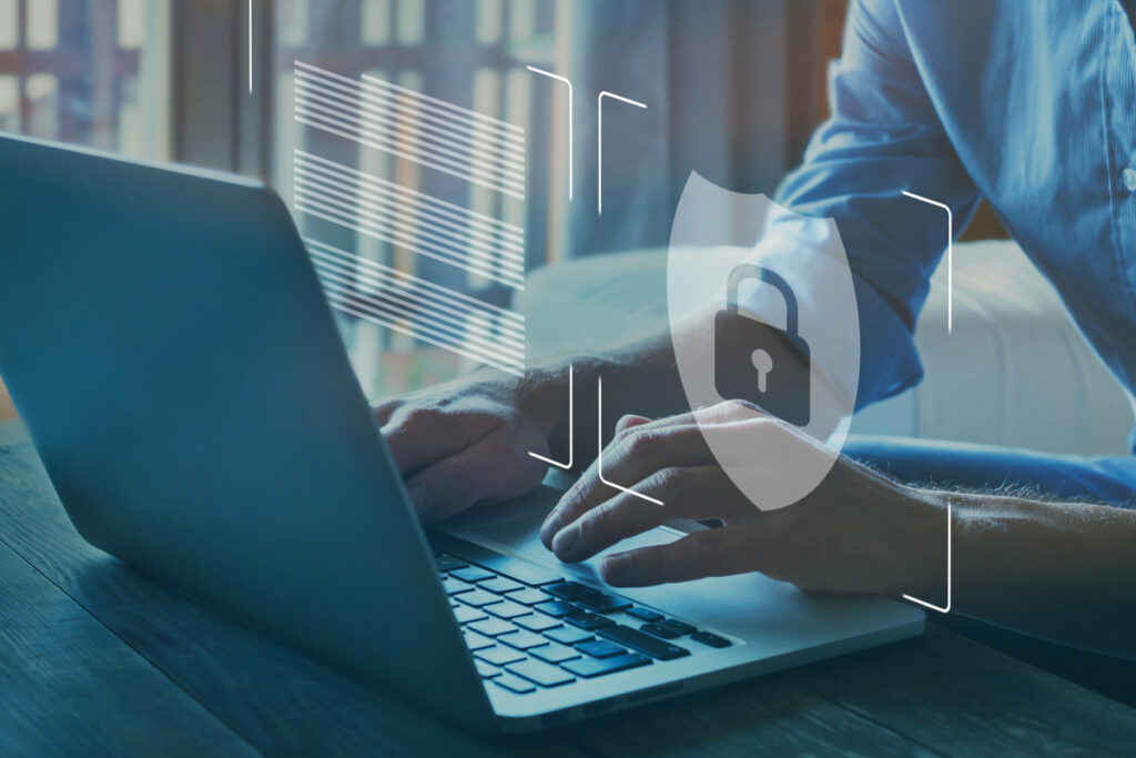 Person working on a laptop with a padlock symbol to represent cybersecurity services