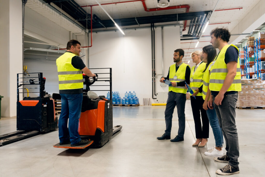 Warehouse worker training other associates on operating material handling equipment